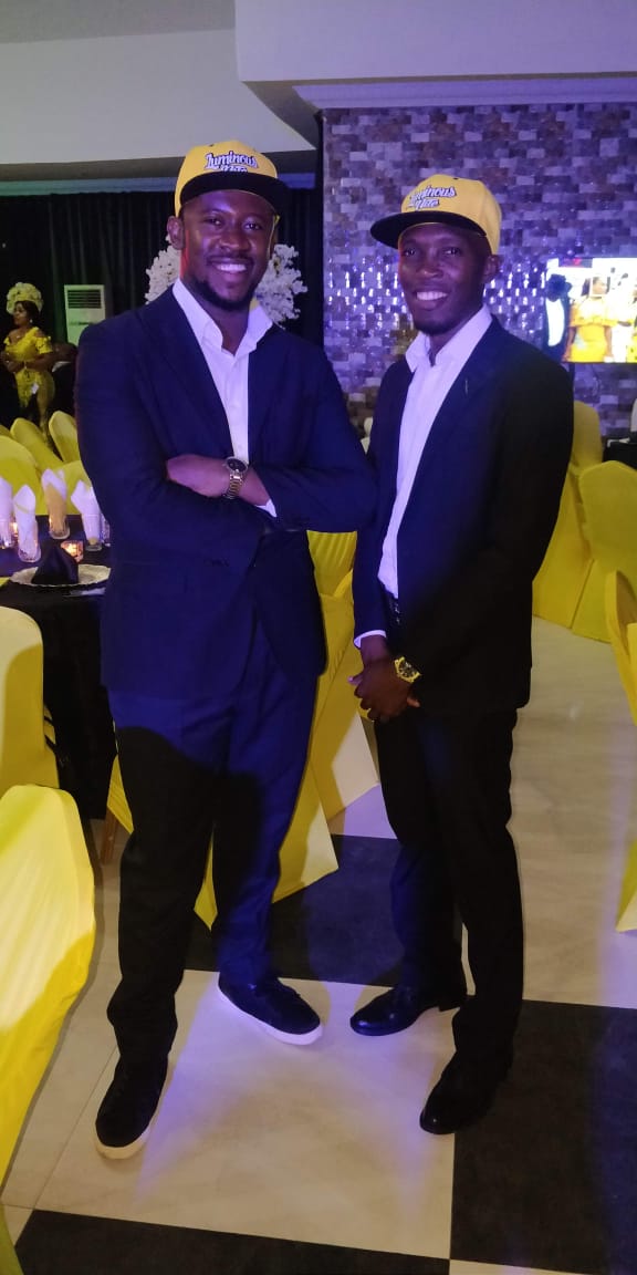 Two guests in navy suits and branded caps at the dinner
