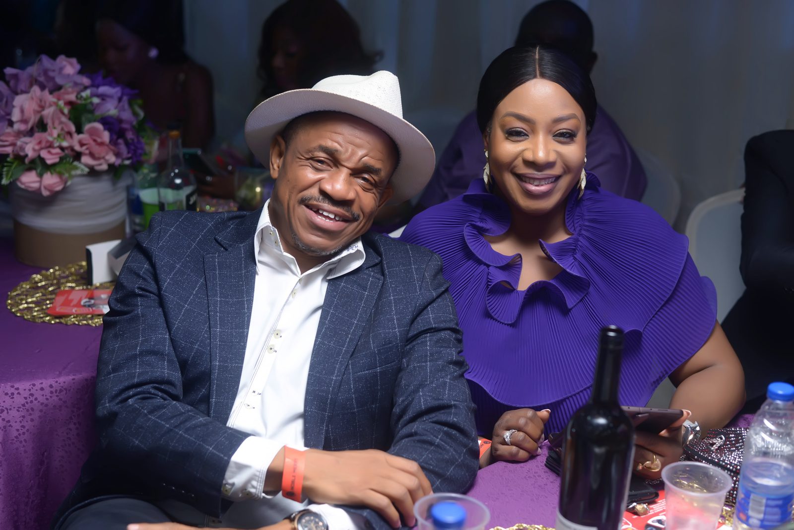 A couple smiling together, the gentleman in a pale fedora