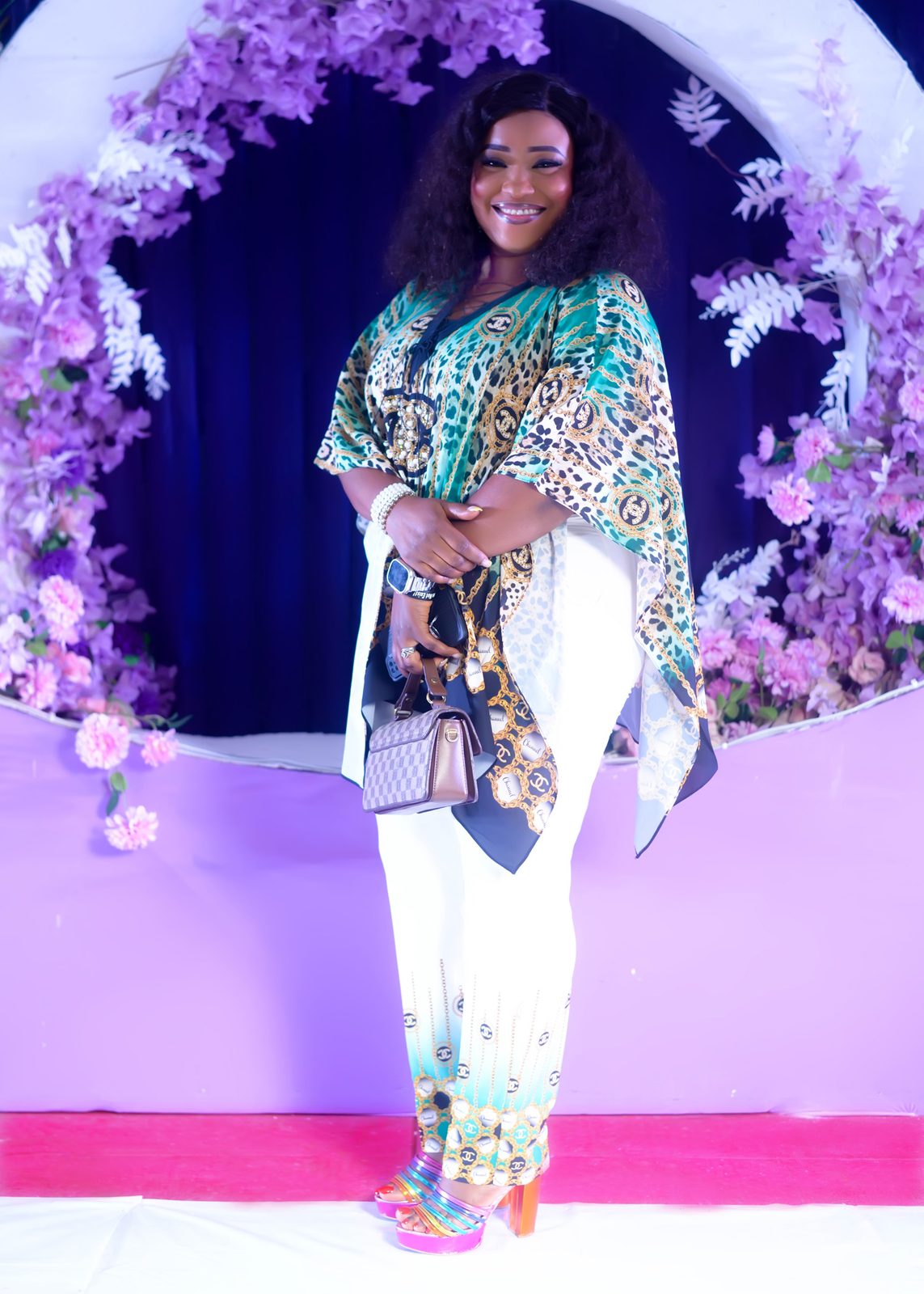 A guest in a patterned top and white trousers