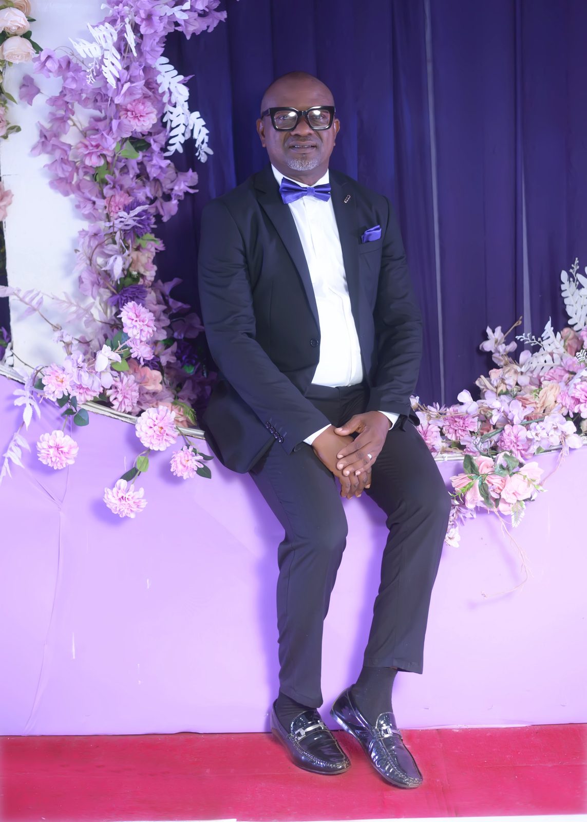 A guest seated in a tailored tuxedo by the arch