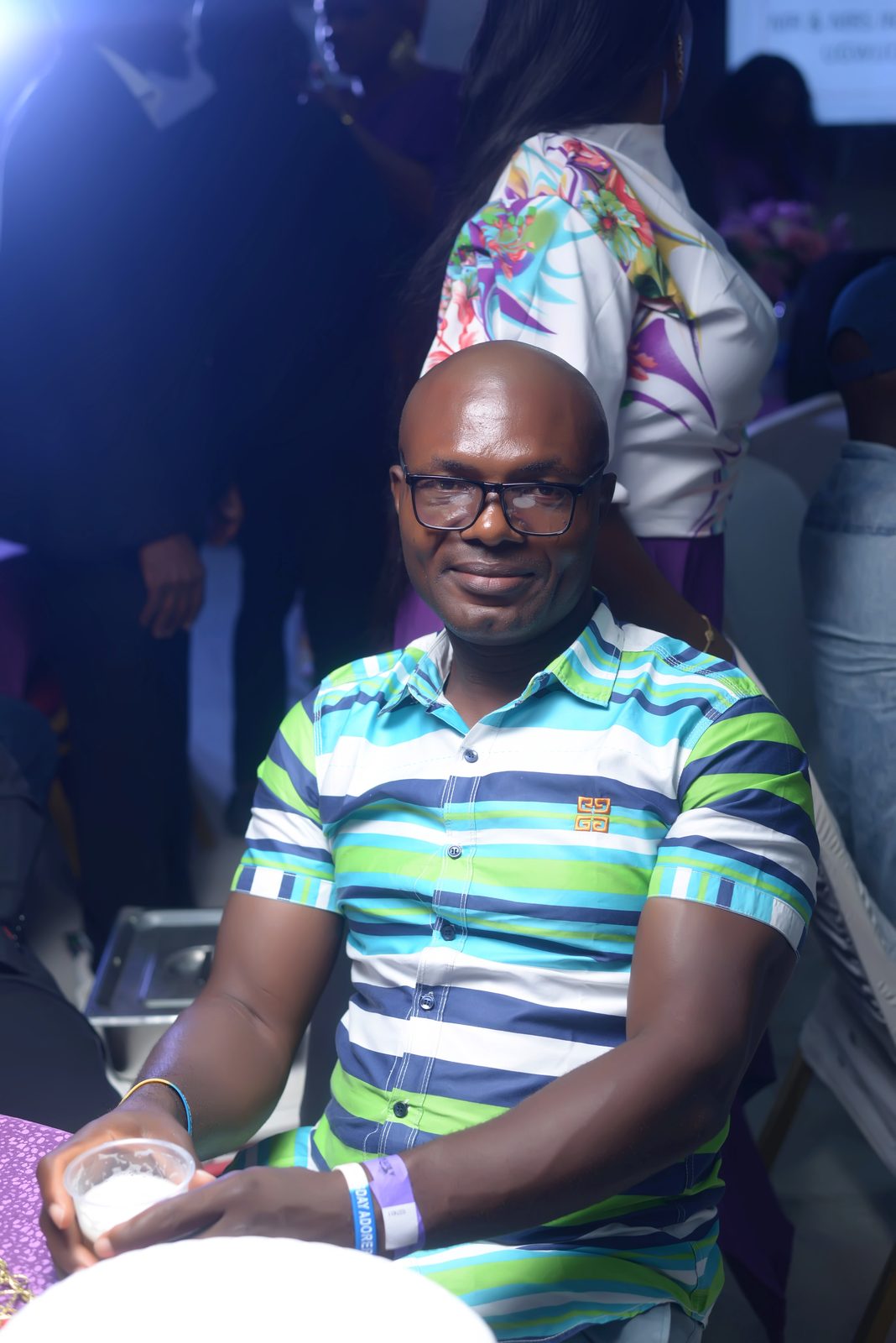 A guest in a bright striped shirt, glass in hand
