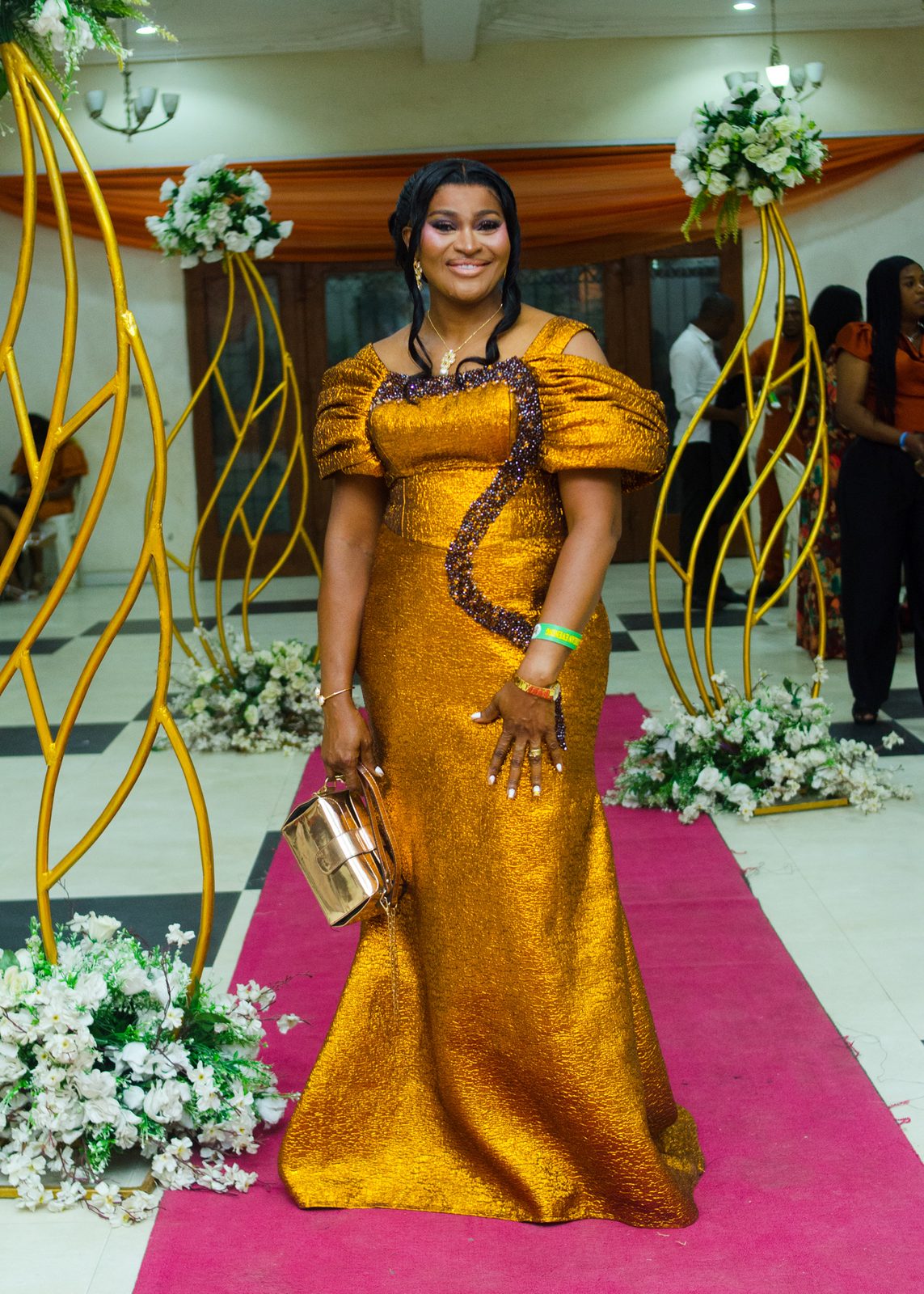A guest in a gold gown on the red carpet