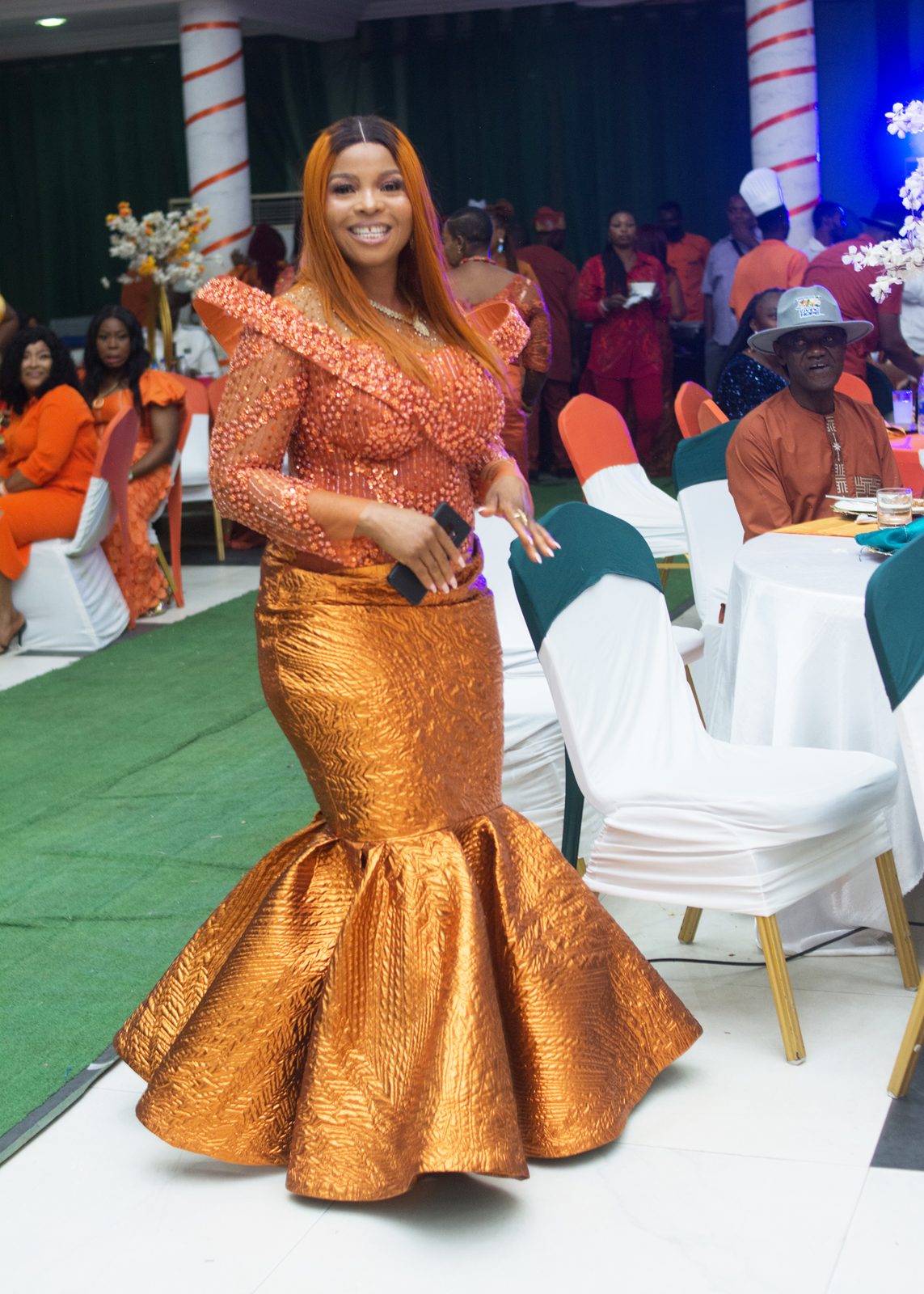 A guest in a fitted gold mermaid gown on the runway